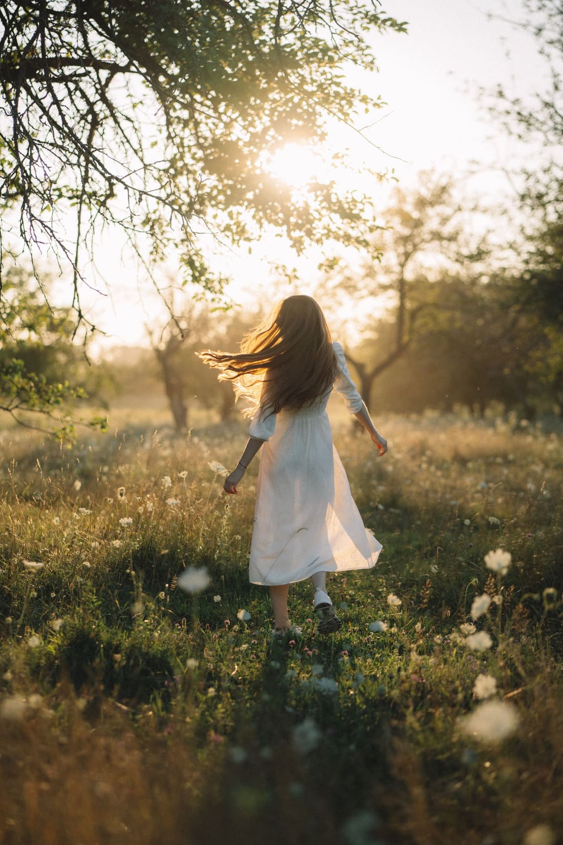 A woman walking free through a sunlit meadow